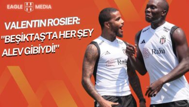 Beşiktaş antrenmanında Valentin Rosier ve Vincent Aboubakar neşeli bir şekilde sohbet ediyor. İki oyuncu, siyah-beyazlı takım formasıyla çim sahada yan yana duruyor; dostça bir anı paylaşıyorlar.